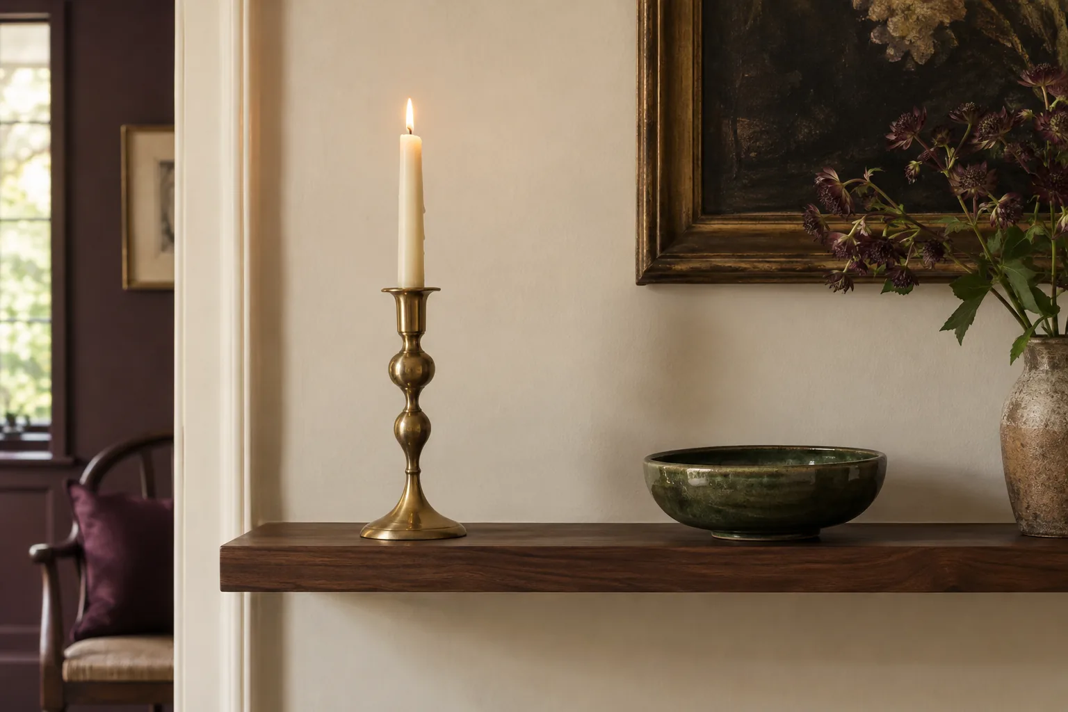 One single sculptural brass candlestick standing confidently alone on a narrow walnut shelf beside a low green ceramic bowl, plenty of breathing room and asymmetrical arrangement, no matching partner