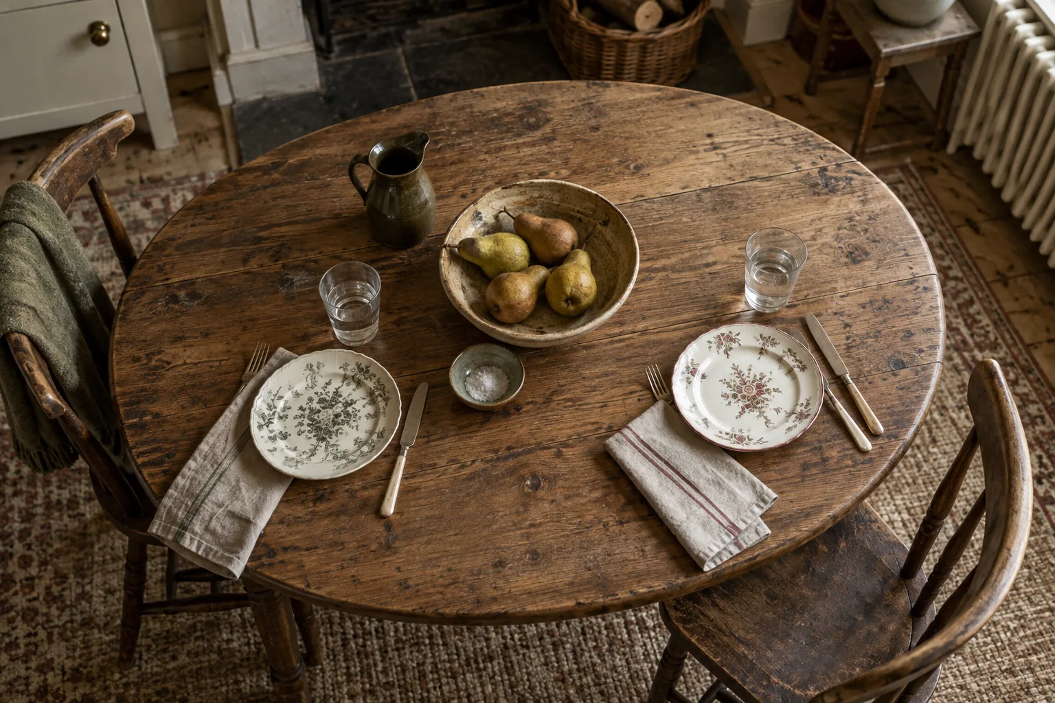 Mixed floral plates and plain glasses set for two on an oak table.