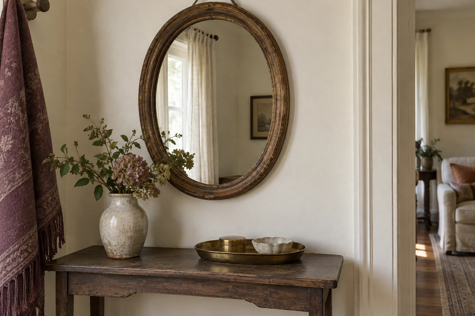 Illustrative oval old mirror above a console with a ceramic vase